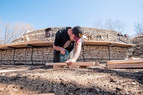 MIKE SUDOMA / WINNIPEG FREE PRESS  
(Left to right) Mackenzie Jackson of Design Built, cuts pieces of wood to complete a bench which surrounds the midewiwin lodge structure on the river banks across from the Forks Market Friday afternoon. The benches and surrounding areas around the lodge will be used as space for people of all ages and abilities to take part in demonstrations and teachings taking place.
May 7, 2021