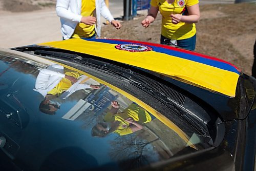 Daniel Crump / Winnipeg Free Press. Andres Veloza (left) and Samy Pena (right) tape a Colombian flag to their vehicle in preparation form a rally calling for an end to the violence against protestors in Colombia. Simultaneous rallied were held at the Canadian Museum for Human Rights and the Manitoba Legislature as well as a vehicle rally that looped between the two locations. May 8, 2021.