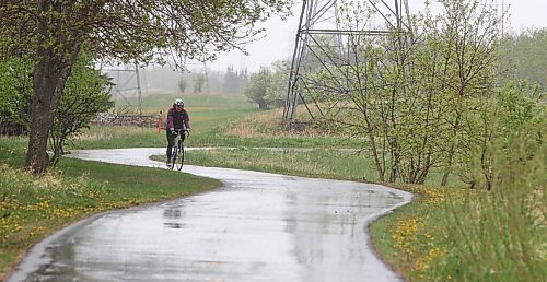 MIKE DEAL / WINNIPEG FREE PRESS
A cyclist makes their way along the Bishop Grandin Greenway during a steady rain Thursday afternoon. 
210520 - Thursday, May 20, 2021