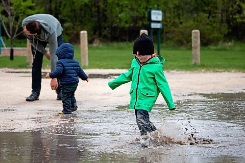 Daniel Crump / Winnipeg Free Press. 3-year-old Charlie McPhail splashes his way through a puddle in a parking lot by Sir John Franklin Park. The McPhail family is making the best of current public health restrictions and wet weekend weather. May 19, 2021.