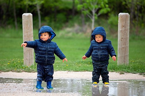 Daniel Crump / Winnipeg Free Press. Year and a half old twins Eddie (left) and Gil (right) Mcphail splash in a parking lot puddle near Sir John Franklin Park on a rainy Saturday afternoon. May 19, 2021.