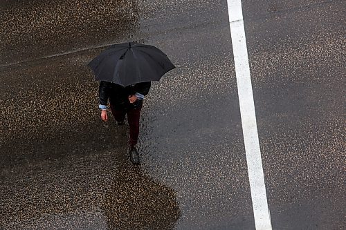 MIKE DEAL / WINNIPEG FREE PRESS
A wet Portage Avenue gleams while an umbrella toting pedestrian walks towards their destination Wednesday afternoon.
210609 - Wednesday, June 09, 2021.