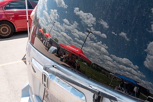 ALEX LUPUL / WINNIPEG FREE PRESS  

Vendors are reflected in the back of a parked vehicle at he Inaugural Farmer's and Artisans' Market outside of the Dakota Fieldhouse in Winnipeg on Thursday, June 17, 2021. More than a dozen vendors were on site selling items ranging from food to homegrown crafts.