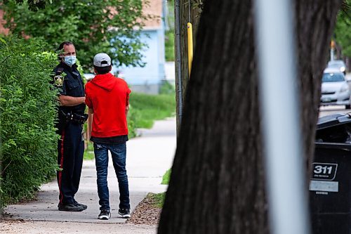 Daniel Crump / Winnipeg Free Press. A police speaks to a youth on the sidewalk where a 12-year-old boy was stabbed Friday evening. The young victim succumb to his injuries and the incident is considered a homicide. June 19, 2021.