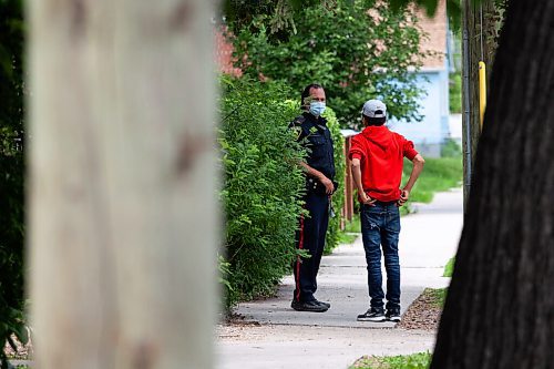 Daniel Crump / Winnipeg Free Press. A police speaks to a youth on the sidewalk where a 12-year-old boy was fatally stabbed Friday evening. The young victim succumb to his injuries and the incident is considered a homicide. June 19, 2021.