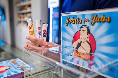 MIKAELA MACKENZIE / WINNIPEG FREE PRESS

Cannabis specialist Adam El-Gabalawy holds a few joints in front of the entry box for the new Joints for Jabs pro-vaccination program at the Osborne Delta 9 Cannabis Store in Winnipeg on Monday, June 21, 2021. For Temur story.
Winnipeg Free Press 2021.