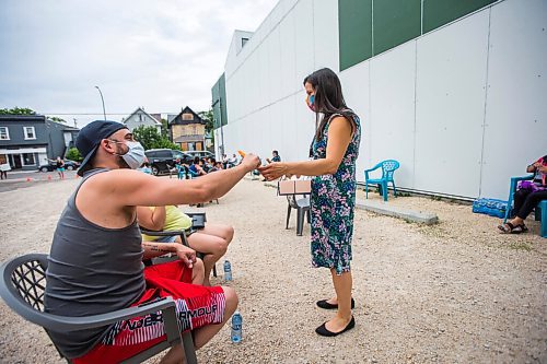 MIKAELA MACKENZIE / WINNIPEG FREE PRESS

Jordan McLachlan takes a freezie from Melanie Houde while in line at a pop-up vaccine clinic at the North End Women's Centre in Winnipeg on Wednesday, June 23, 2021. Standup.
Winnipeg Free Press 2021.