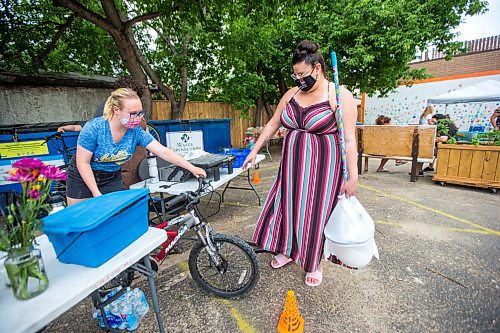 MIKAELA MACKENZIE / WINNIPEG FREE PRESS

Lasha Mackedenski (with The Wrench) hands Brittany Anderson one of 30 free children's bikes (as she also holds one of the cleaning/PPE kits given to each vaccinated individual) while at a pop-up vaccine clinic at the North End Women's Centre in Winnipeg on Wednesday, June 23, 2021. Standup.
Winnipeg Free Press 2021.