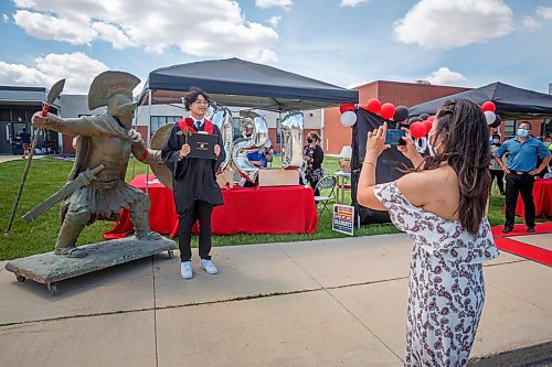 MIKE DEAL / WINNIPEG FREE PRESS
Grade 12 grad J. M. Quizon gets his photo taken by his mom, Elma Samgalang, after driving up to receive his diploma during a drive-up grad outside École Secondaire Sisler High School (1360 Redwood Ave) Thursday afternoon.
210624 - Thursday, June 24, 2021.