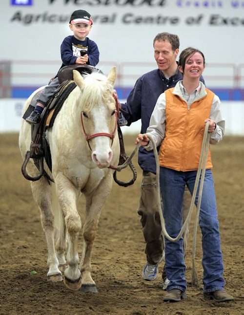 Brandon Sun Two-year-old Hawkin McDermot rides a quarter horse with some help from Scott Erickson at the Royal Manitoba Winter Fair, Tuesday afternoon. Fairgoers got to learn about quarterhorses during the new "Royal Experiences" event. (Colin Corneau/Brandon Sun)