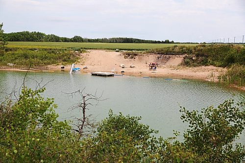 MIKE DEAL / WINNIPEG FREE PRESS
A water filled rock quarry with a slide and floating dock just off the Taylor Road north of Petersfield, MB, where a four-year-old boy drowned on Sunday according to the Selkirk RCMP. 
210705 - Monday, July 5, 2021