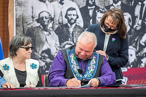 MIKAELA MACKENZIE / WINNIPEG FREE PRESS

Manitoba Metis Federation (MMF) president David Chartrand signs the agreement, which gives the MMF formal recognition to lead the Manitoba Metis and represent them, as MMF vice president Leah LaPlante (left) and Chartrand's wife, Glorian Chartrand, watch at a signing ceremony at Upper Fort Garry Heritage Provincial Park in Winnipeg on Tuesday, July 6, 2021. For Carol Sanders story.
Winnipeg Free Press 2021.