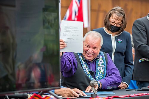 MIKAELA MACKENZIE / WINNIPEG FREE PRESS

Manitoba Metis Federation (MMF) president David Chartrand holds up a signed copy of the agreement, which gives the MMF formal recognition to lead the Manitoba Metis and represent them, as Chartrand's wife, Glorian Chartrand, watches at a signing ceremony at Upper Fort Garry Heritage Provincial Park in Winnipeg on Tuesday, July 6, 2021. For Carol Sanders story.
Winnipeg Free Press 2021.