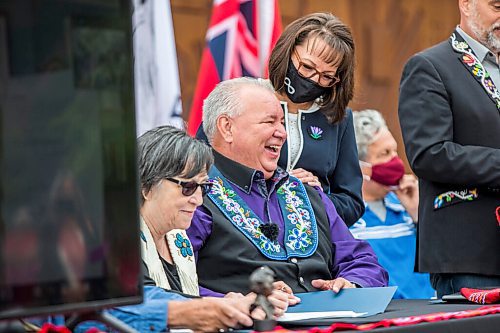 MIKAELA MACKENZIE / WINNIPEG FREE PRESS

Manitoba Metis Federation (MMF) president David Chartrand laughs while signing multiple copies of the agreement, which gives the MMF formal recognition to lead the Manitoba Metis and represent them, as MMF vice president Leah LaPlante (left) and Chartrand's wife, Glorian Chartrand, watch at a signing ceremony at Upper Fort Garry Heritage Provincial Park in Winnipeg on Tuesday, July 6, 2021. For Carol Sanders story.
Winnipeg Free Press 2021.