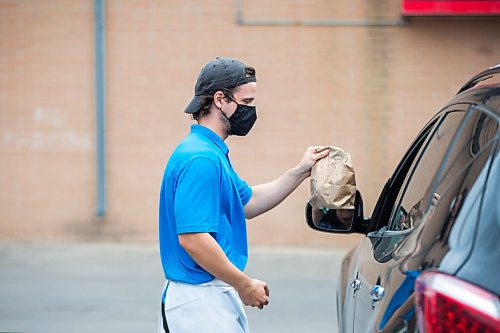 MIKAELA MACKENZIE / WINNIPEG FREE PRESS

Brendan Ellis brings orders out to folks waiting in their cars at the Dairi-Wip Drive In, one of the more iconic burger joints in town, in Winnipeg on Tuesday, July 6, 2021. For Dave Sanderson story.
Winnipeg Free Press 2021.