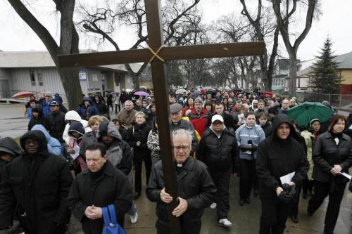MIKE.DEAL@FREEPRESS.MB.CA 100402 - Friday, April 2nd, 2010 Archbishop James Weisgerber carries the cross at the beginning of the procession from the Holy Ghost Church as it moves East on Pritchard towards Main Street while hundreds follow him during the 23rd annual Public Way of the Cross. The 2km route went East on Pritchard to Main, North until Redwood then they turned West until they got to Salter. Turning South the procession headed to Selkirk then back East to the Holy Ghost Church. MIKE DEAL / WINNIPEG FREE PRESS