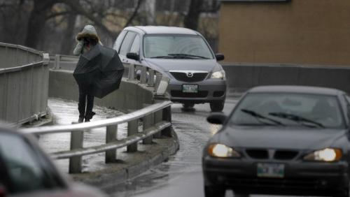 MIKE.DEAL@FREEPRESS.MB.CA 100402 - Friday, April 2nd, 2010 A pedestrian takes out her umbrella as she walks across the Midtown Bridge during the afternoon downpour. MIKE DEAL / WINNIPEG FREE PRESS