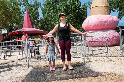 Daniel Crump / Winnipeg Free Press. Nathalie Roche and her daughter, Léa Roche, stand in front of a large misting fan setup at Tinkertown to help people stay cool. Temperatures on Saturday afternoon reached into the low thirties. July 10, 2021.