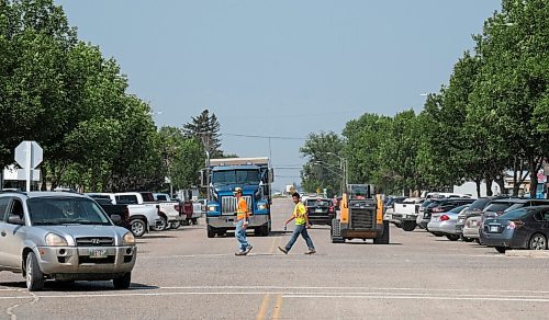 MIKE DEAL / WINNIPEG FREE PRESS
Construction workers cross Dennis Street in the town of Gladstone, MB, where Eileen Clarke the MLA for Agassiz is from.
210716 - Friday, July 16, 2021.