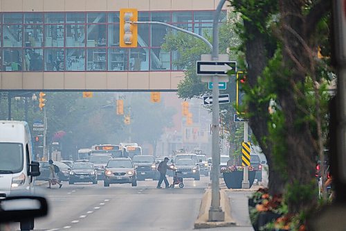 MIKE DEAL / WINNIPEG FREE PRESS
A smokey haze fills the air from forest fires as pedestrians cross Portage Avenue in Winnipegs Downtown Monday afternoon. 
210719 - Monday, July 19, 2021