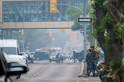 MIKE DEAL / WINNIPEG FREE PRESS
A smokey haze fills the air from forest fires as pedestrians cross Portage Avenue in Winnipegs Downtown Monday afternoon. 
210719 - Monday, July 19, 2021.