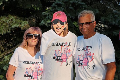 Canstar Community News Eleanor Mislawchuk, left, and her husband Fred pose in the t-shirts they'll wear when they watch their son Tyler's Olympic race on July 25. Their daughter Madison couldn't attend the July 15 photo shoot; the Mislawchuks stuck a cut-out of her head on a tripod so she could still be there. Eleanor brings cut-outs of Madison and Fred and uses them to cheer Tyler on at his races when the whole family can't make it. (GABRIELLE PICHÉ/CANSTAR COMMUNITY NEWS/HEADLINER)
