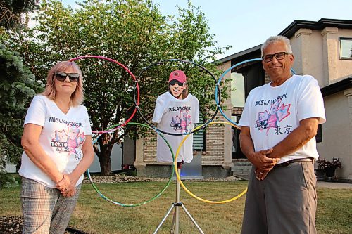 Canstar Community News Eleanor Mislawchuk, left, and her husband Fred pose with the Olympic rings set up they've made in their front yard. Their daughter Madison couldn't attend the July 15 photo shoot; the Mislawchuks stuck a cut-out of her head on a tripod so she could still be there. Eleanor brings cut-outs of Madison and Fred and uses them to cheer Tyler on at his races when the whole family can't make it. (GABRIELLE PICHÉ/CANSTAR COMMUNITY NEWS/HEADLINER)