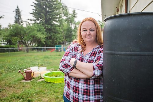 MIKAELA MACKENZIE / WINNIPEG FREE PRESS

Morden resident Theresa Dueck poses for a portrait by one of the rain barrels in her yard on Thursday, July 22, 2021. She has been collecting rain water and the water usually wasted before shower/bath water gets warm to water her vegetable garden. For Kevin Rollason story.
Winnipeg Free Press 2021.
