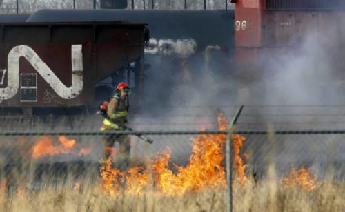 MIKE.DEAL@FREEPRESS.MB.CA 100409 - Friday, April 9th, 2010 Fire fighters work to put out a grass fire that got very close to some parked railway cars including a diesel engine along the edges of the CPR North Transcona Railyards between Springfield Road and Bluecher Road. MIKE DEAL / WINNIPEG FREE PRESS