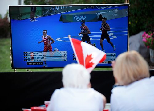 JOHN WOODS / WINNIPEG FREE PRESS
Josephine Leddy, grandmother of Canadian Triathlete Tyler Mislawchuck waves her flag and cheers him on as he races at the Tokyo Olympics at his parents house in Oak Bluff Sunday, July 25, 2021. 

Reporter: Sawatzky