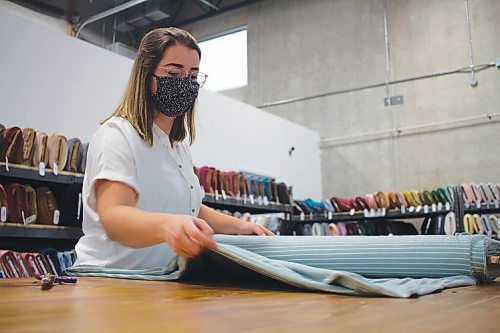 Canstar Community News Brianne Davison, manager of The Fabric Snob, measures and cuts from a roll of fabric at the Manitoba businesss new retail location in Oak Bluff.