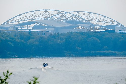 MIKE DEAL / WINNIPEG FREE PRESS
A motor boat zips along the Red River where it runs along River Road in St. Vital with smoke hazed IG Field rising in the distance.
210729 - Thursday, July 29, 2021.