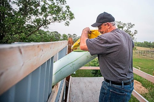 MIKAELA MACKENZIE / WINNIPEG FREE PRESS

Roger Stearns pours dog kibble down a chute into the enclosure while remaining hidden from the bears at Black Bear Rescue Manitoba near Stonewall on Wednesday, July 7, 2021. For Eva Wasney story.
Winnipeg Free Press 2021.