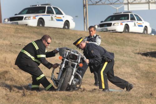 JOE.BRYKSA@FREEPRESS.MB.Ca Local-  RCMP and a West St Paul fire department members move a motorcycle that was involved in a mva Saturday afternoon at a off ramp on Main St and the Perimeter Hyw- West St Paul  fire department member said the man who was driving was conscious when taken into ambulance and to hospital for examination-Apr 17, 2010- JOE BRYKSA/WINNIPEG FREE PRESS