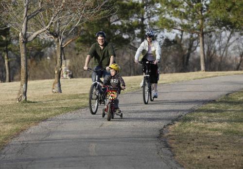 BORIS.MINKEVICH@FREEPRESS.MB.CA  100418 BORIS MINKEVICH / WINNIPEG FREE PRESS King's Park -Spencer Strijack,2, leads his parents Stuart and Christine, and little sister Evelyn,2,(in basket behind mom but not seen). The family spent the evening cycling through the park.