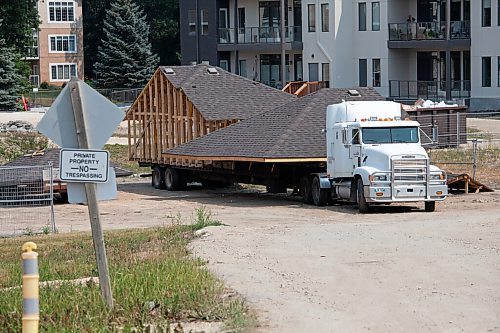 Daniel Crump / Winnipeg Free Press. The roof of a house is loaded onto a flatbed and waits to be moved from the Roblin Grove development. Earlier in the day other portions of the house got stuck on Roblin Blvd during transport leaving a wake of destruction in their path. August 7, 2021.