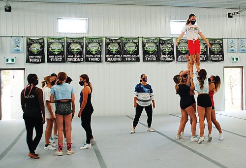 Canstar Community News Coaches work on lifts with cheer athletes at Legacy Cheerleading.