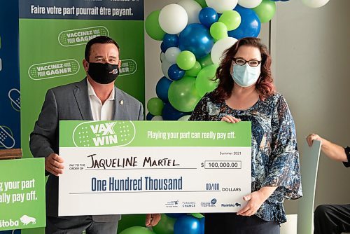 ALEX LUPUL / WINNIPEG FREE PRESS  

Crown Services Minister Jeff Wharton hands a cheque to Jaqueline Martel, one of the Vax to Win Lottery winners, at the Leila Avenue vaccination site on August 17, 2021.