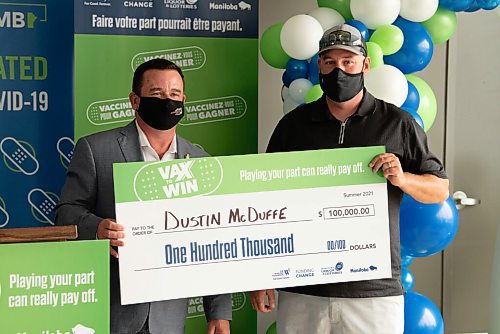 ALEX LUPUL / WINNIPEG FREE PRESS  

Crown Services Minister Jeff Wharton hands a cheque to Dustin McDuffe, one of the Vax to Win Lottery winners, at the Leila Avenue vaccination site on August 17, 2021.