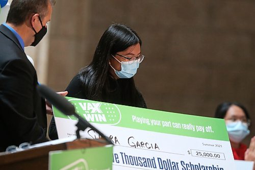 WINNIPEG FREE PRESS/SHANNON VANRAES
Advanced Education Minister Wayne Ewasko hands a giant check to Vax to Win scholarship recipient Shaira Garcia at the Manitoba Legislative Building August 23, 2021.