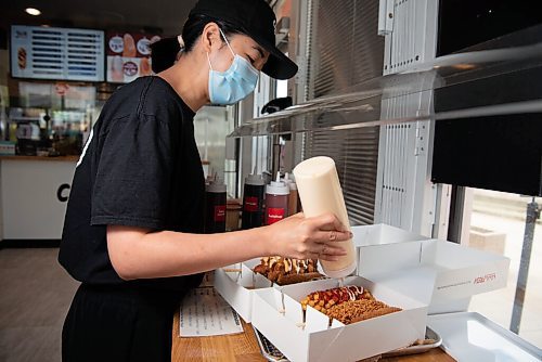 ALEX LUPUL / WINNIPEG FREE PRESS  

Jane Khau, owner of Chung Chun Rice Dog's Jefferson Avenue location in Winnipeg, adds additional sauces and seasonings to a selection of their Korean-style hotdogs on August, 25, 2021.