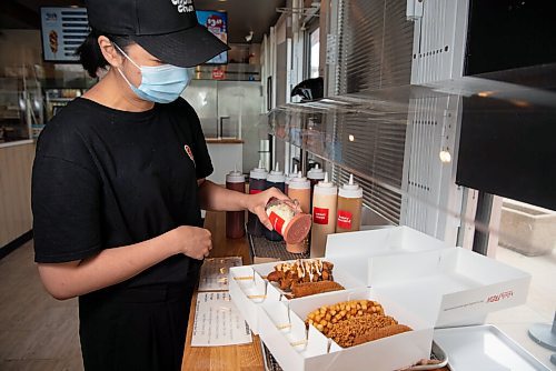 ALEX LUPUL / WINNIPEG FREE PRESS  

Jane Khau, owner of Chung Chun Rice Dog's Jefferson Avenue location in Winnipeg, adds additional sauces and seasonings to a selection of their Korean-style hotdogs on August, 25, 2021.