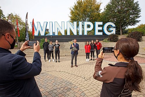 MIKE DEAL / WINNIPEG FREE PRESS
Mayor Brian Bowman holds the Duckworth Challenge Trophy in front of the Winnipeg sign at The Forks, flanked by UofM Bisons athletes (from left) Owen Schwartz (men's volleyball), Jessica Tsai (soccer), and Taylor Randall (women's basketball), UofW Wesmen athletes, Chantal Boulet (soccer), Mikaela Cameron (womens volleyball), Darian Picklyk (men's volleyball).
The 30th anniversary of the Duckworth Challenge kicks off later this week re-igniting the annual rivalry series between the two Winnipeg universities that now includes men's and women's basketball, men's and women's volleyball, and women's soccer.
210920 - Monday, September 20, 2021.