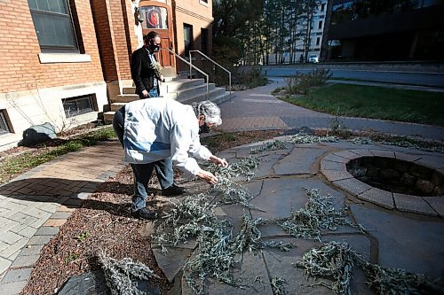 JOHN WOODS / WINNIPEG FREE PRESS
Sylvia Genaille, councillor and elder at the National Centre for Truth and Reconciliation, collects sage in their medicine garden as Jesse Boiteau, senior archivist, looks on at the centre in Winnipeg Wednesday, September 22, 2021. 

Reporter: Martin