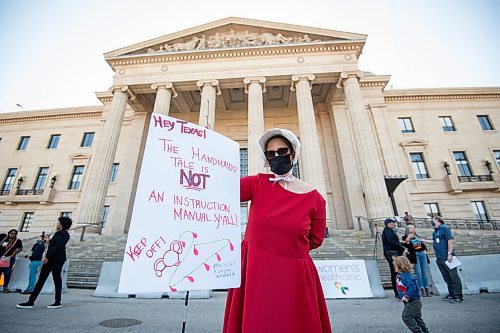 MIKE SUDOMA / Winnipeg Free Press
Katrina Greer of Handmaid Local 204/431 hold up a sign while in her traditional handmaids clothing during the Rally for Reproductive Justice event Saturday
October 2, 2021