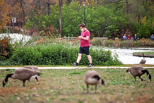 Daniel Crump / Winnipeg Free Press. A person checks their phone as they walk by the duck pond in Assiniboine Park Saturday afternoon. October 9, 2021.