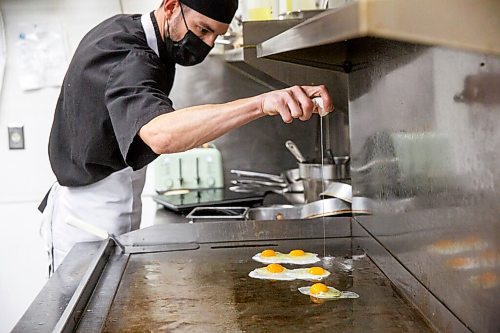 MIKE DEAL / WINNIPEG FREE PRESS
John Lindenbach, kitchen manager at The Oakwood Cafe, crakes some eggs, Thursday afternoon.
The Oakwood Cafe, 660 Osborne Street, a South Osborne mainstay that celebrated its 30th anniversary last year, albeit not very celebratory. Wendy May purchased the restaurant five years ago but hasn't paused to bake herself a 5th anniversary cake either, things were such a struggle the last 20 months.
211021 - Thursday, October 21, 2021.