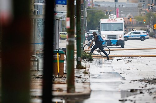 JOHN WOODS / WINNIPEG FREE PRESS
A cyclist jumps across some water as firefighters work a fire scene at a building in the 800 block of Main Street Sunday, October 24, 2021

Reporter: Standup