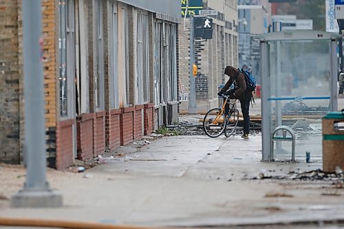 JOHN WOODS / WINNIPEG FREE PRESS
A cyclist gets on their bike as firefighters work a fire scene at a building in the 800 block of Main Street Sunday, October 24, 2021

Reporter: Standup