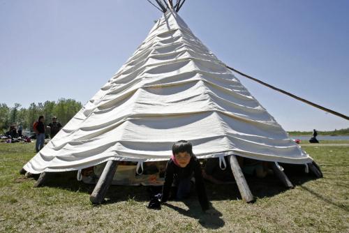 MIKE.DEAL@FREEPRESS.MB.CA 100520 - Thursday, May 20th, 2010 OPASKWAYAK CREE NATION Terrianna Constance, 7, a grade one student at Joe E. Ross School looks out from under a teepee that slid up the polls from the wind during the traditional camp and community feast. See Nick Martin story. MIKE DEAL / WINNIPEG FREE PRESS